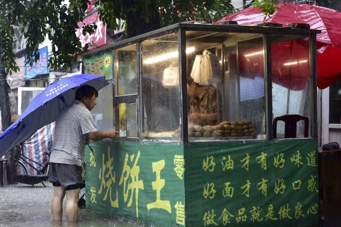 A resident buys breakfast from a street vendor in Tianjin. Floods in neighbouring Hebei have killed at least 130 people, with 110 others missing. Photo: Xinhua