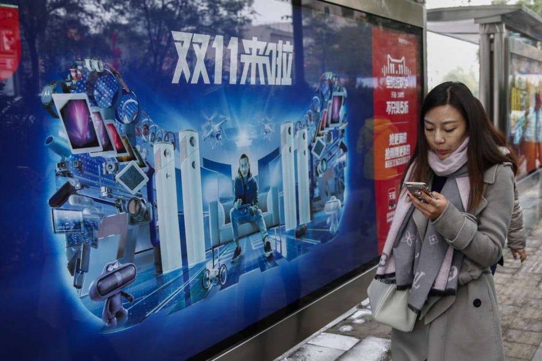 A woman views her smartphone as she walks past an advertisement for online shopping in Beijing. Online retail sales in China are expected to double over the next three years. Photo: EPA