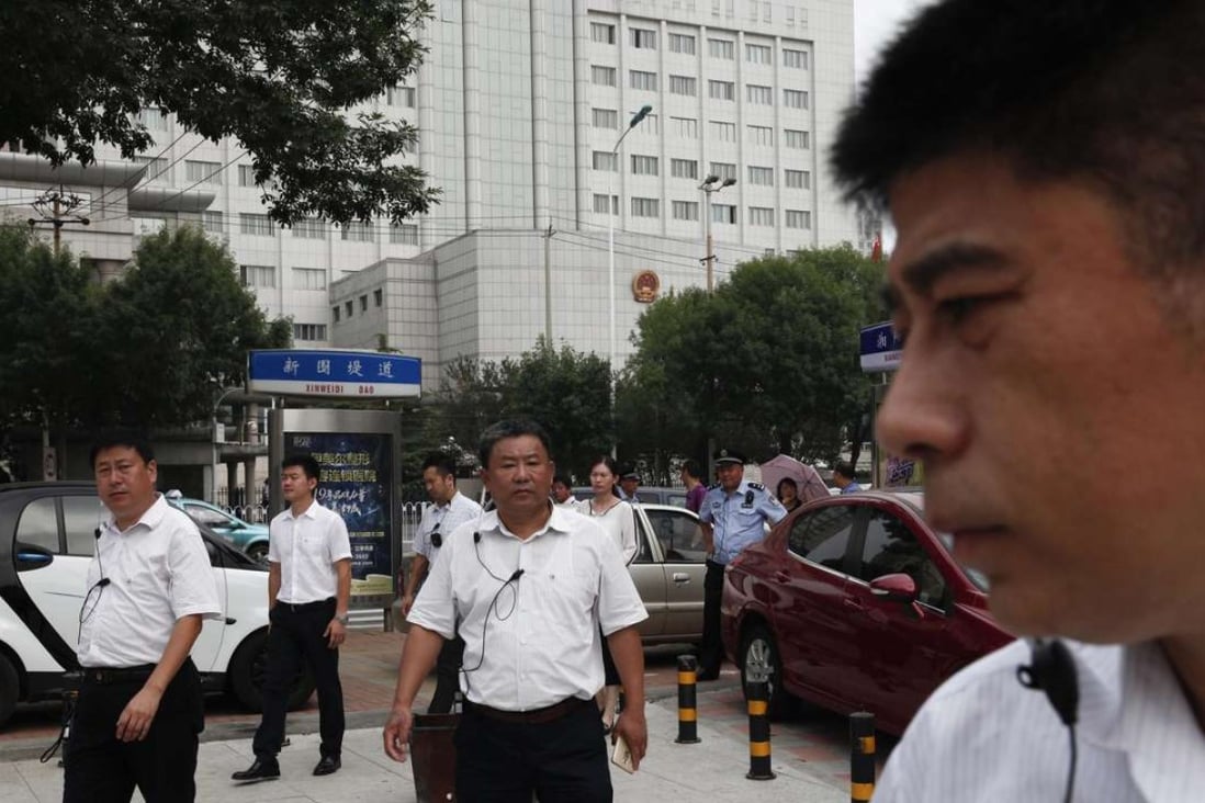 Chinese men in plain clothes, believed to be security personnel, follow journalists in an apparent attempt to affect photo and video coverage outside the Tianjin No 2 Intermediate People's Court on Wednesday. Photo: EPA