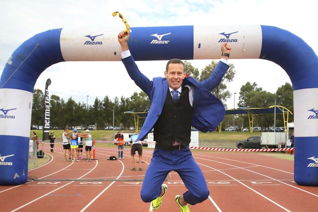 Mike Tozer celebrates running a half-marathon in a three-piece suit in record time. Photo: Drew Grigg/Yet Another Idea