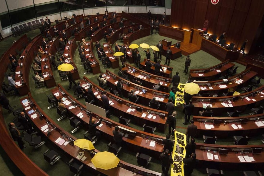 Pan-democratic lawmakers file out of the Legislative Council chamber holding yellow umbrellas and banners calling for genuine universal suffrage ahead of the chief executive’s policy address in January 2015. Photo: EPA