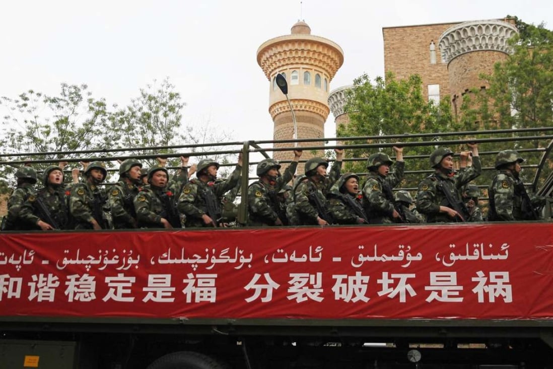 Paramilitary policemen in Xinjiang behind a banner reading "Harmony and stability are blessings, separation and discord are disasters”. Photo: Reuters
