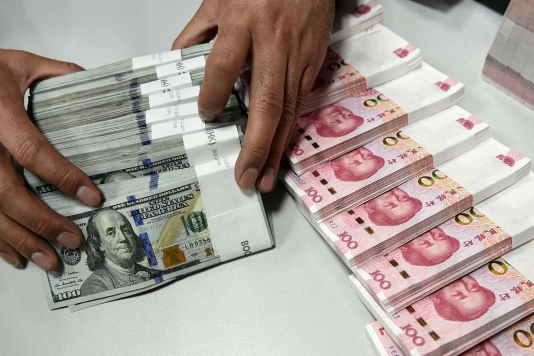 A clerk counts Chinese yuan and US dollar banknotes at a bank in China. Photo: Reuters