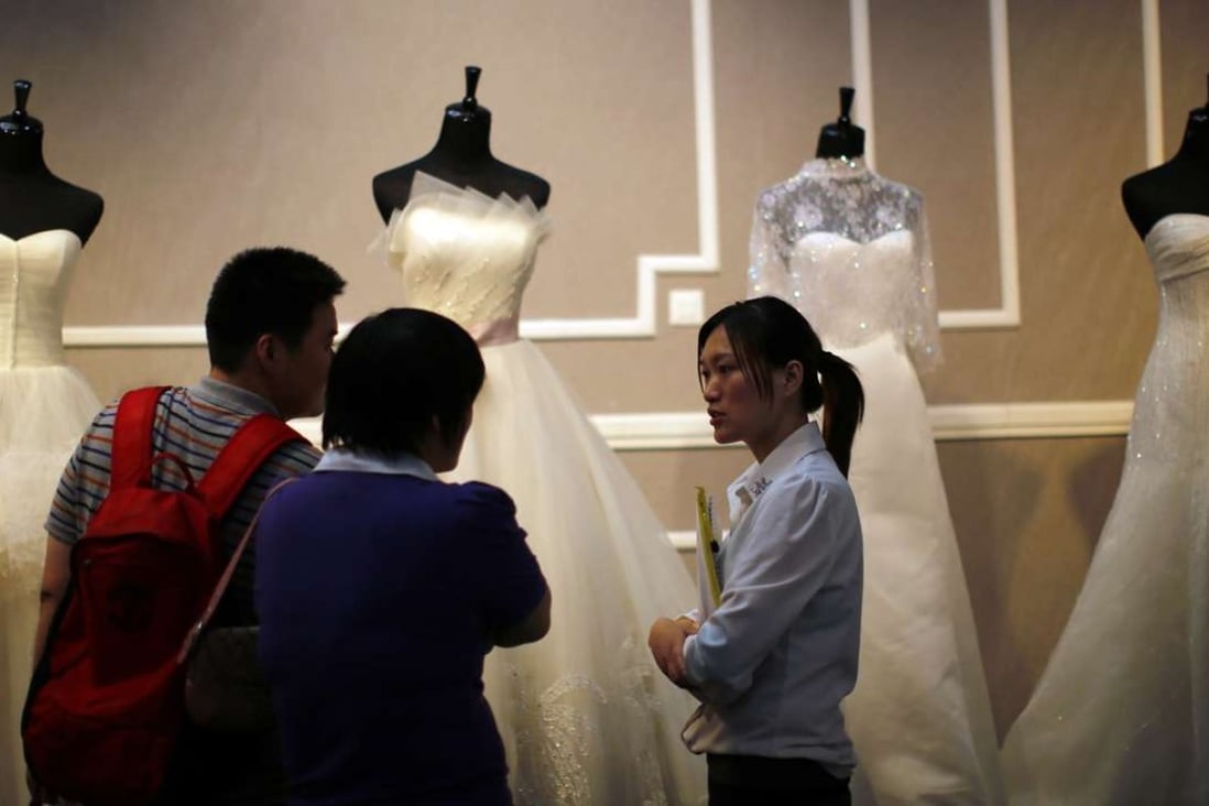 A couple talk to a vendor at a wedding dress stand during a wedding exhibition in downtown Shanghai. Photo: Reuters