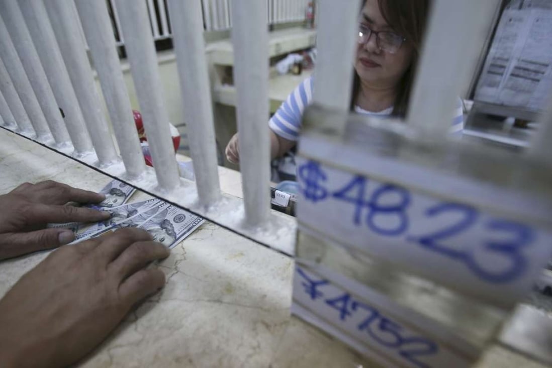 A man changes his US dollar bills to Philippine pesos beside a sign showing the exchange rates at a money changer in Manila, as uncertainties about Philippine President Rodrigo Duterte's policies and flip-flopping pronouncements wereblame dfor foreign selling in the stock market and the peso’s plunge to a seven-year low. Photo: AP