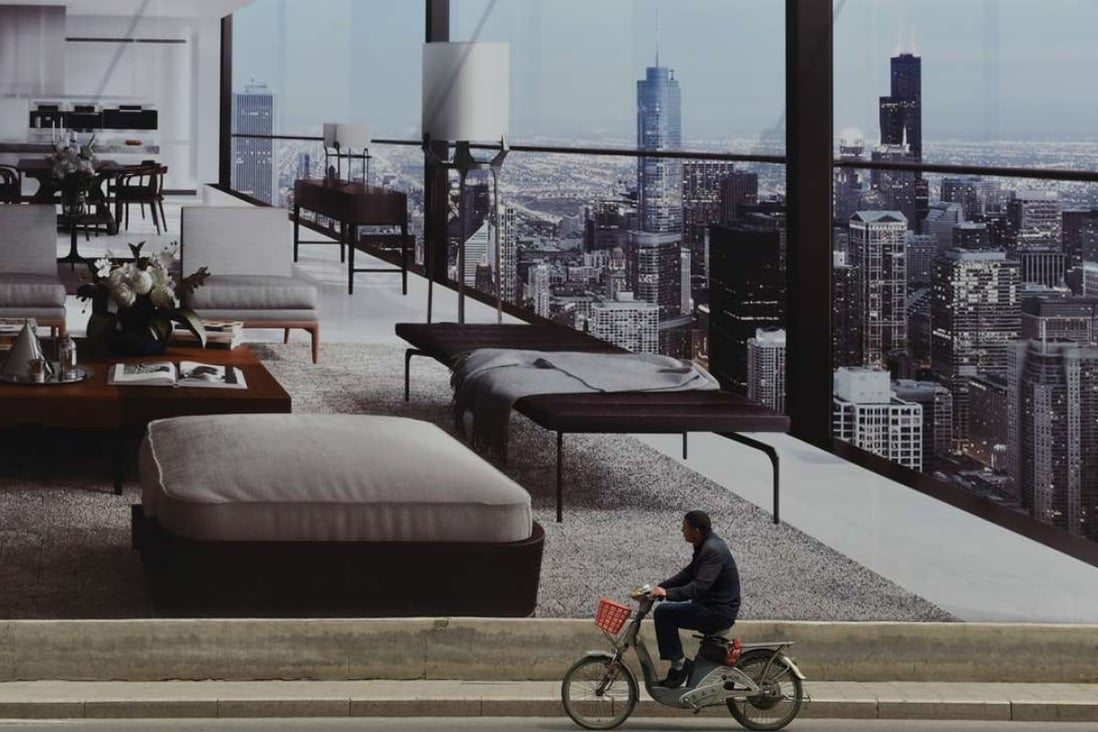 A man cycles past a billboard advertising a new housing complex outside in Beijing. The city is following in the footsteps of Nanjing and Hangzhou, where similar policies restricting home purchases have been introduced. Photo: AFP