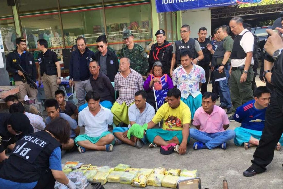 Thai police officers inspect confiscated weapons and drugs after a raid operation leading to the arrest of alleged Golden Triangle drug lord Laota Sanli (second row, left, wearing black) and others, including his family members, at a petrol station in Mae Ai district, Chiang Mai Province. Photo: EPA