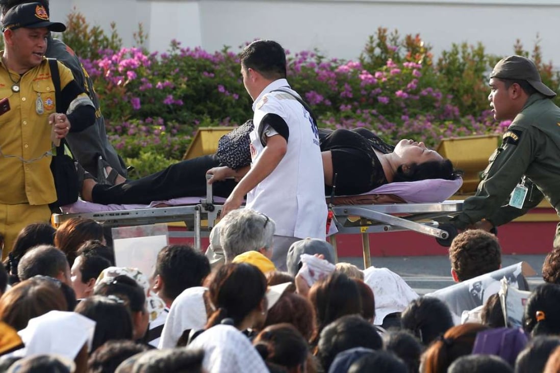 A mourner is attended to after passing out while waiting for the motorcade carrying the body of King Bhumibol Adulyadej. Photo: Reuters