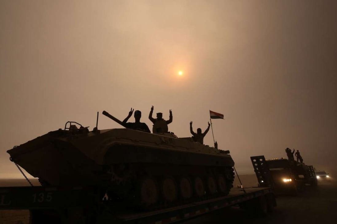 Iraqi forces flash the V-sign as they stand on an infantry fighting vehicle loaded on a truck driving through the Al-Shura area, south of Mosul, on Monday, during an operation to retake the city from the Islamic State group. Photo: AFP