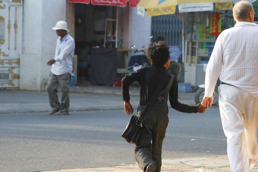 A middle-aged Western man walks hand in hand with a local boy in Phnom Penh. A report of this kind of suspicious behaviour is usually enough to convince Action Pour Les Enfants to begin an investigation. Photo: Courtesy of APLE Cambodia