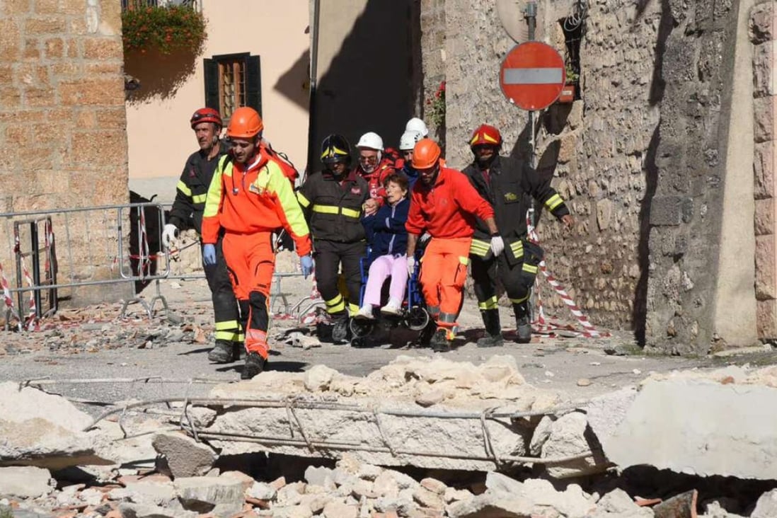 Italian fire fighters help a resident in the town of Norcia after Sunday’s strong earthquake in central Italy. Photo: EPA