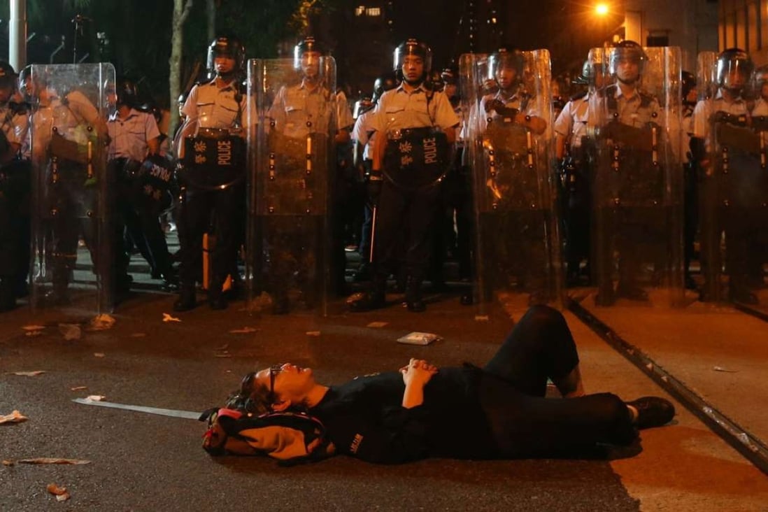 A protester lies down in the street in front of a row of police officers. Photo: K.Y. Cheng