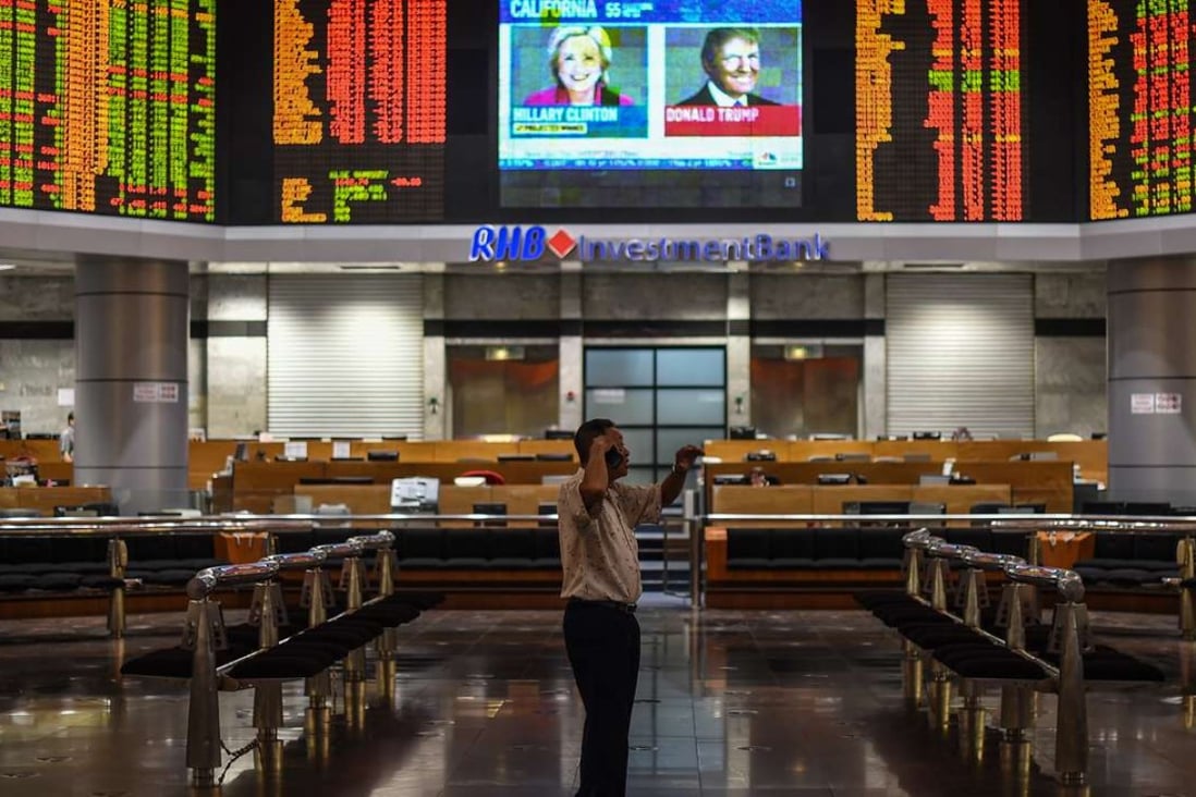 A trader in Kuala Lumpur in front of an electronic board showing stock movements during the US presidential vote. Photo: AFP
