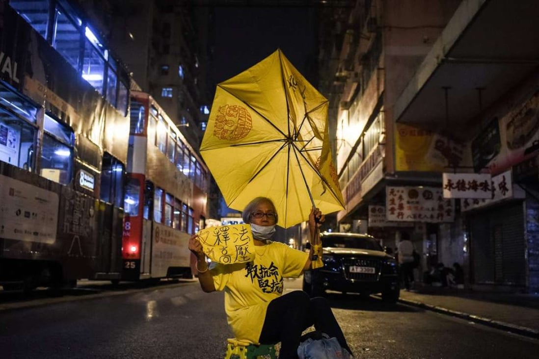 A protestor holds up a yellow umbrella as she protests in a street in Hong Kong last Monday following China's decision to intervene in the oath-taking saga. Photo: AFP