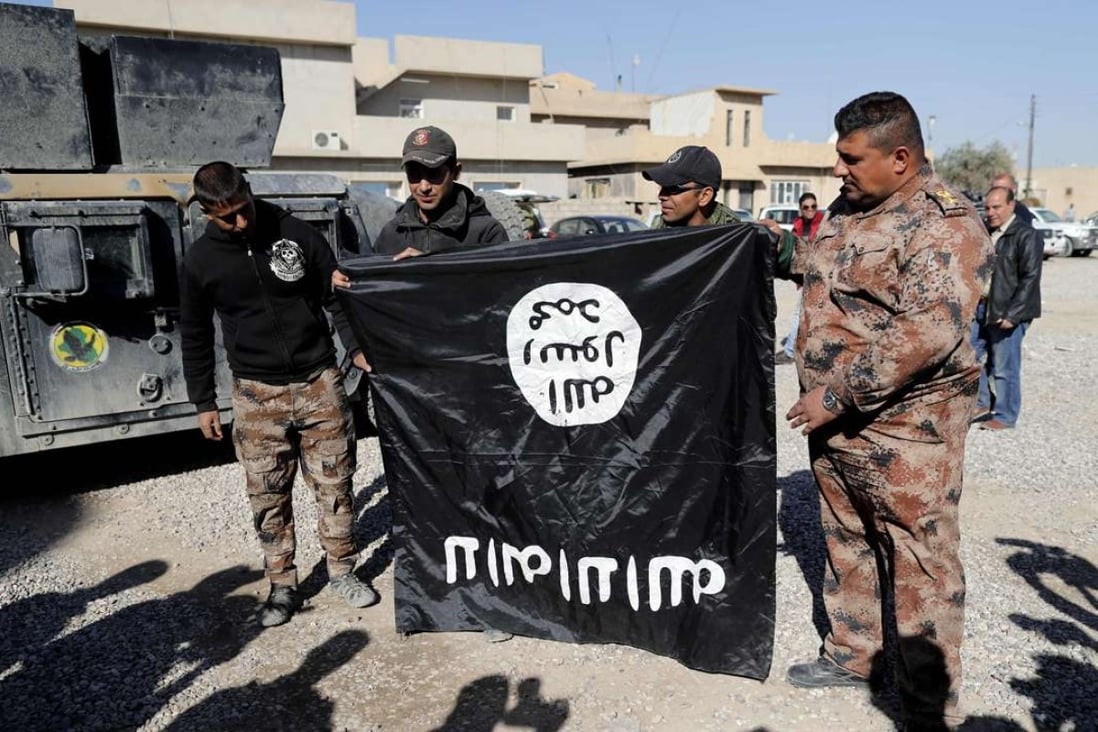 Iraqi army soldiers hold a captured flag from the Islamic State (IS) jihadist group upside-down on Wednesday, near an Iraqi army base in the outskirts of Mosul. Photo: AFP