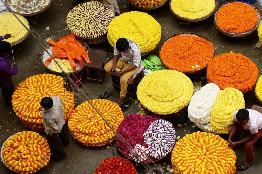 Indian flower vendors wait for customers at a market in Bangalore. Indian businesses have been hit hard by the lack of currency notes in the wake of the government’s decision to ban high denomination notes. Photo: EPA