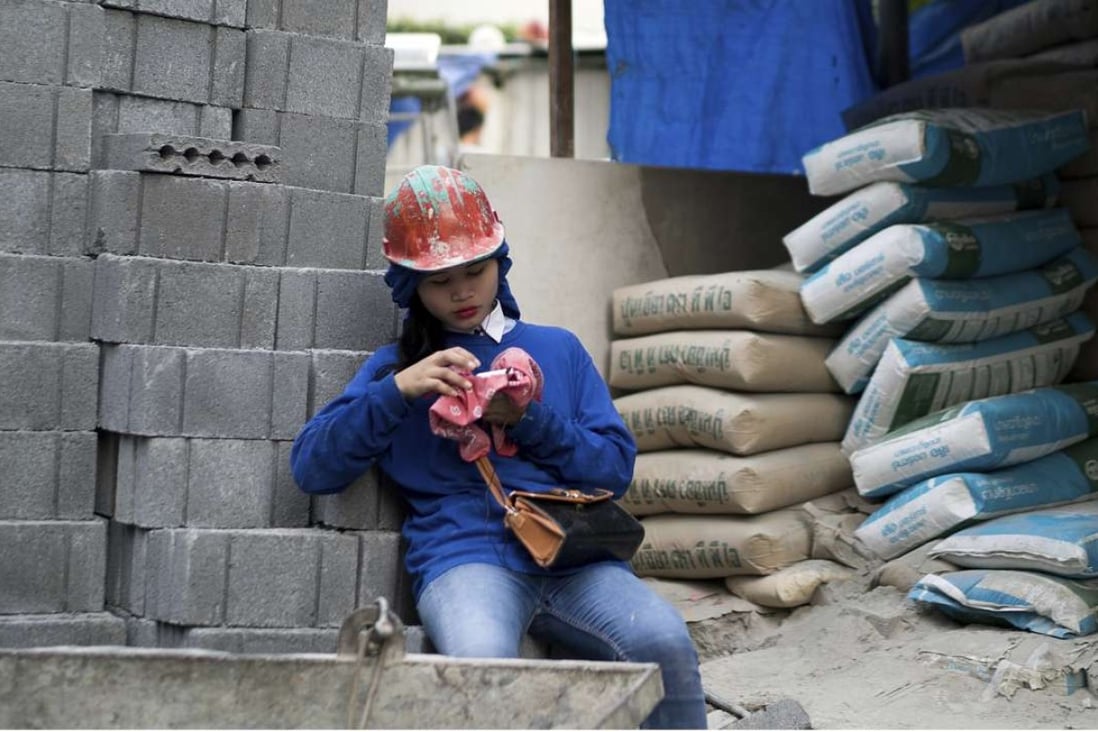 A Cambodian migrant construction worker checks her phone outside a building site in downtown Bangkok, Thailand. The Asia-Pacific region hosts the largest migrant population in the world. Photo: AP