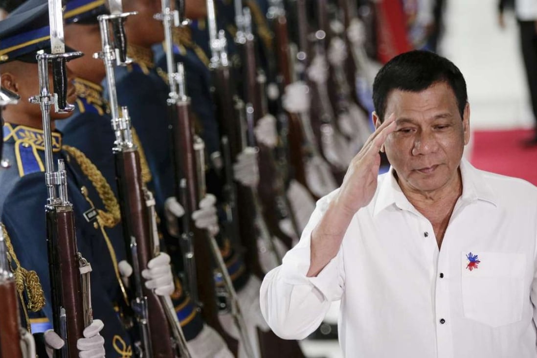 Philippine President Rodrigo Duterte reviews an honour guard on Tuesday during a departure ceremony at the Manila International Airport before departing on a trip to Cambodia and Singapore. Photo: EPA