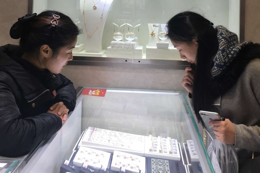 A Chow Tai Seng salesperson advises a customer in a department store outlet in Shanghai. The Shenzhen-based jeweller is planning an IPO to raise 1.46 billion yuan. Photo: Maggie Zhang