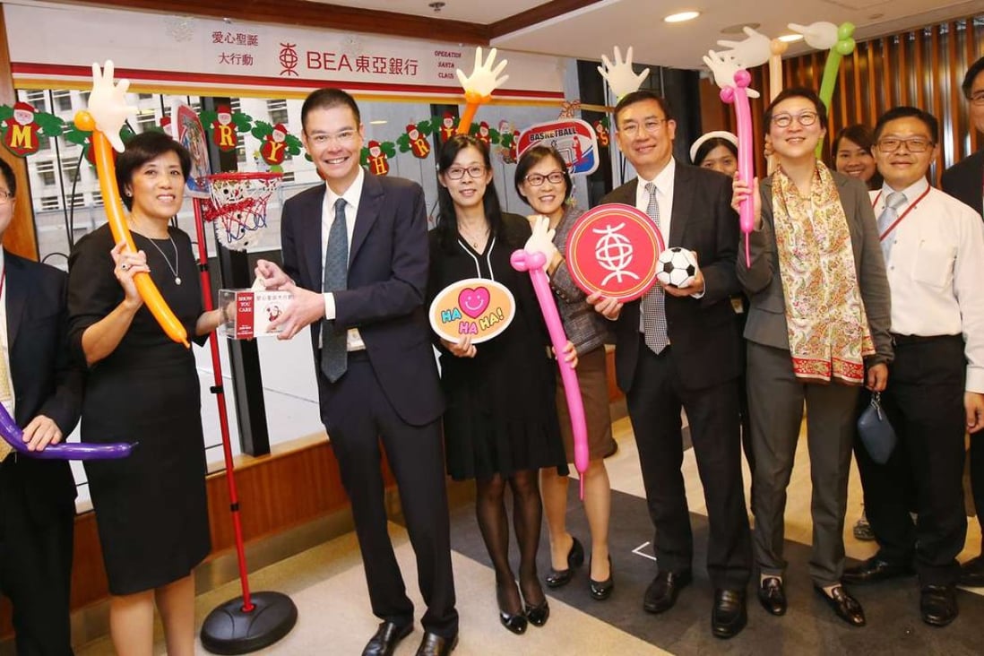 Executive director Adrian Li (third from left), general manager and head of HR Mimi Kam (second left) and other Bank of East Asia staff raise a cheer after a week of charity events. Photos: David Wong