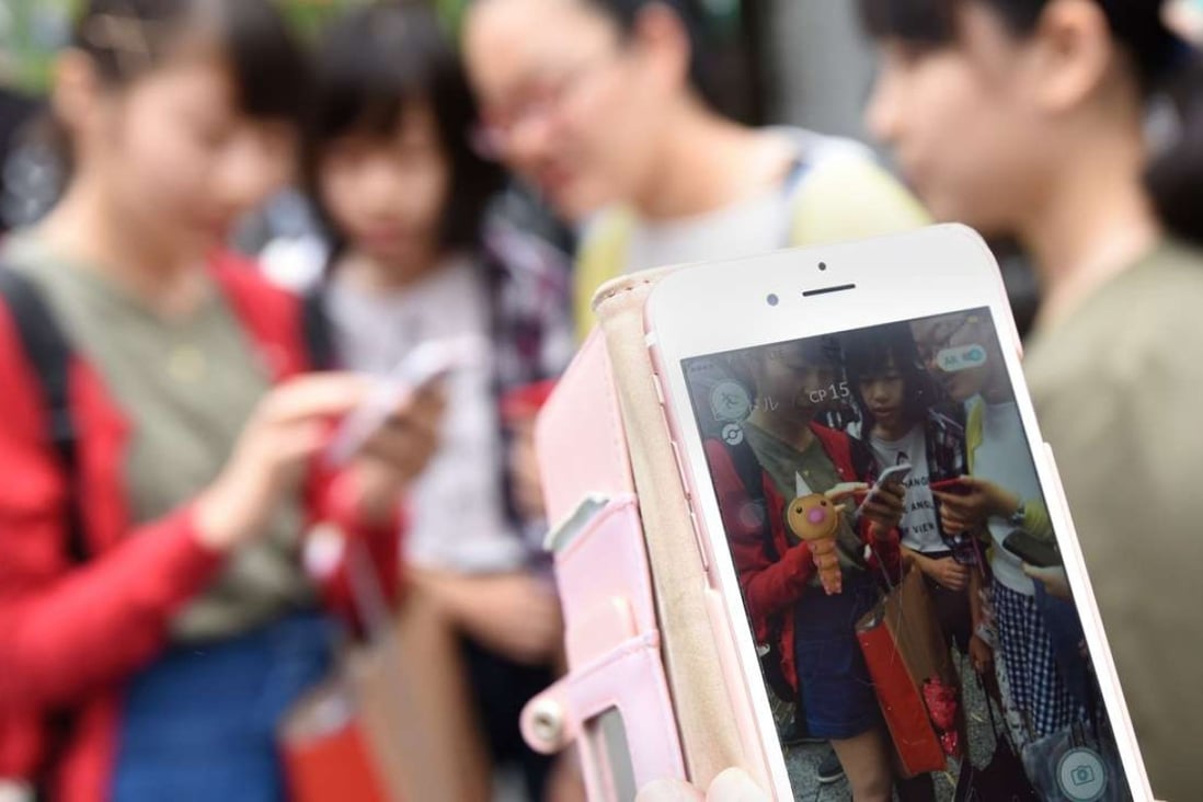 Schoolgirls play Pokemon Go on their mobile phones on a street. Photo: AFP