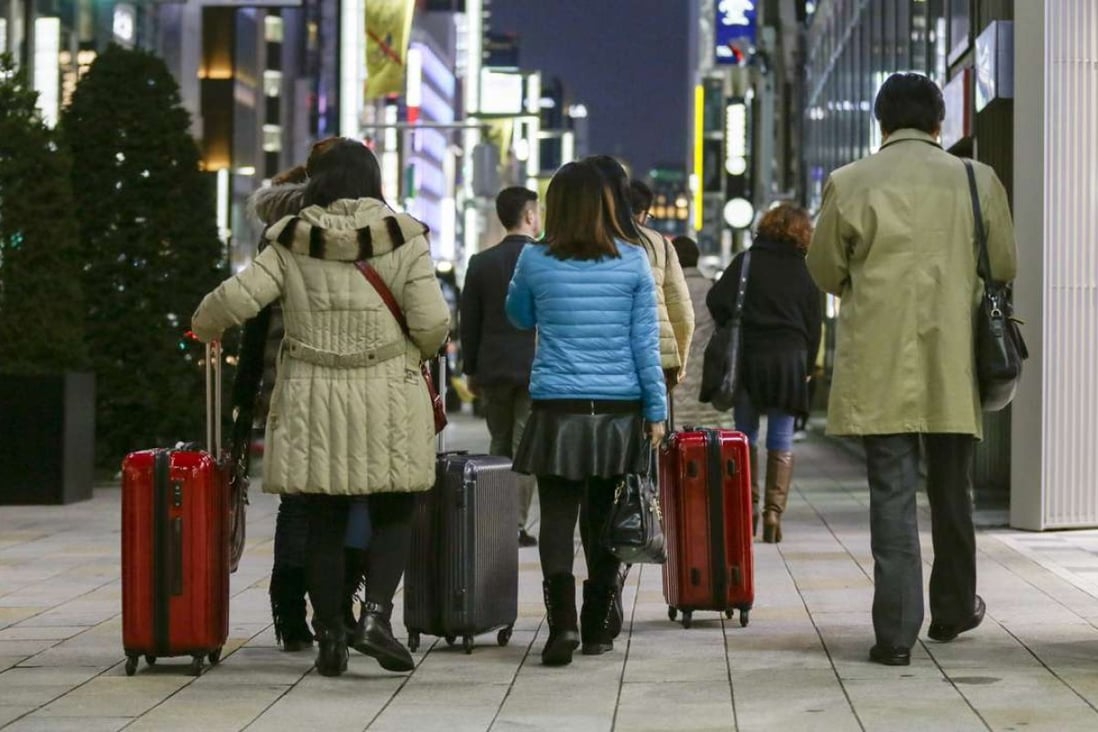 Chinese tourists carry suitcases packed with purchases during bulk buying, known as Bakugai, in central Tokyoin 2015. Photo: EPA