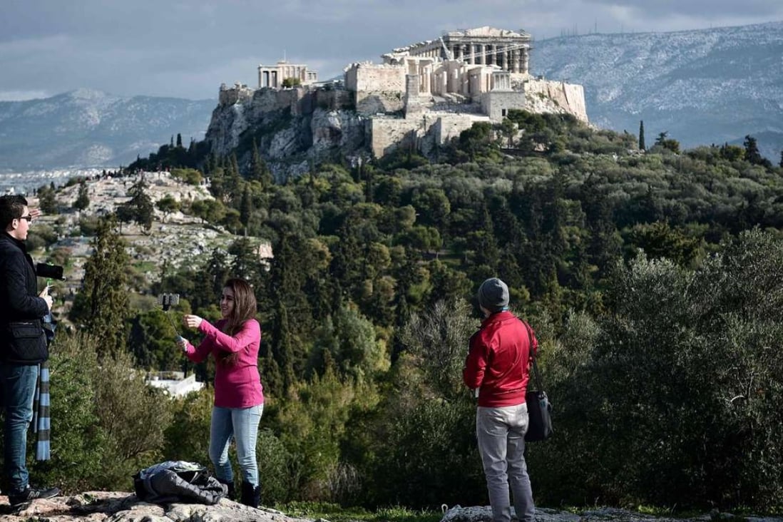 Tourists watch the Acropolis from the Pnyx hill in Athens, Greece. Photo: AFP
