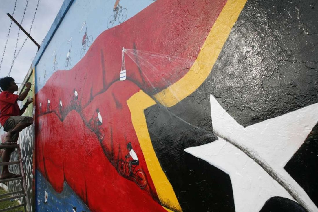 A Timorese youth makes finishing touches on a mural in Dili, East Timor. Photo: AP