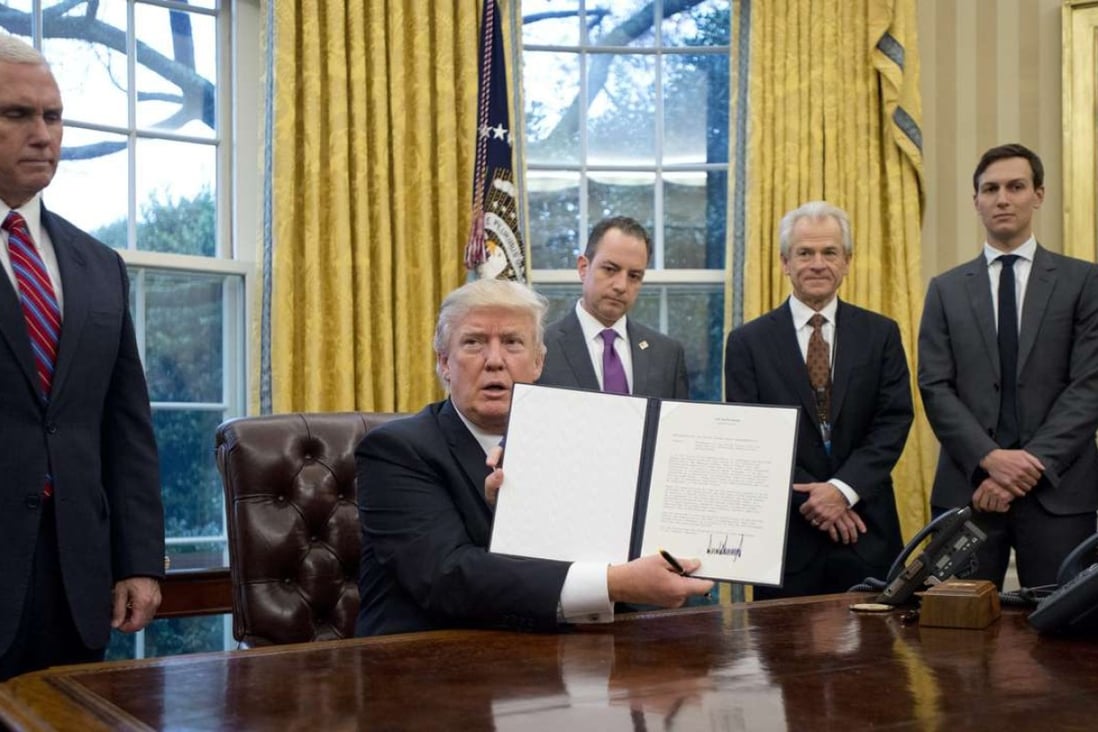 US President Donald Trump holds up an executive order withdrawing the US from the Trans-Pacific Partnership after signing it in the Oval Office of the White House in Washington, DC. Photo: EPA