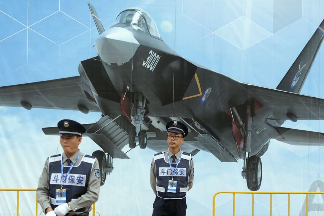 Two security guards stand in front of a poster of China’s Shenyang J/FC-31 stealth fighter at the Zhuhai air show in November 2014. Photo: Dickson Lee