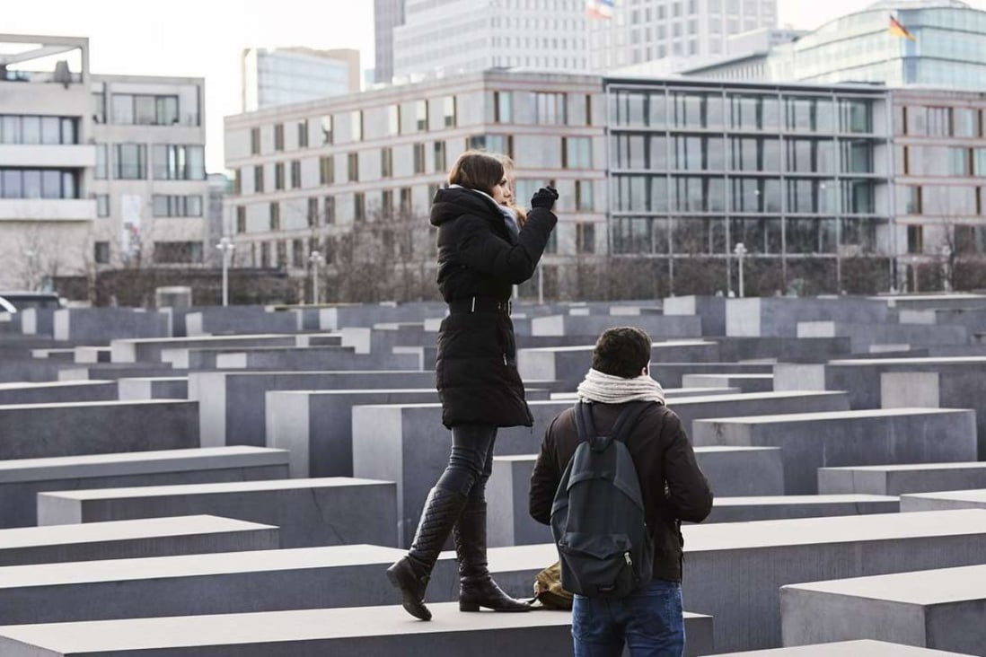 Visitors take photos while standing on the blocks of the Memorial to the Murdered Jews of Europe in Berlin last Thursday. Photo: EPA
