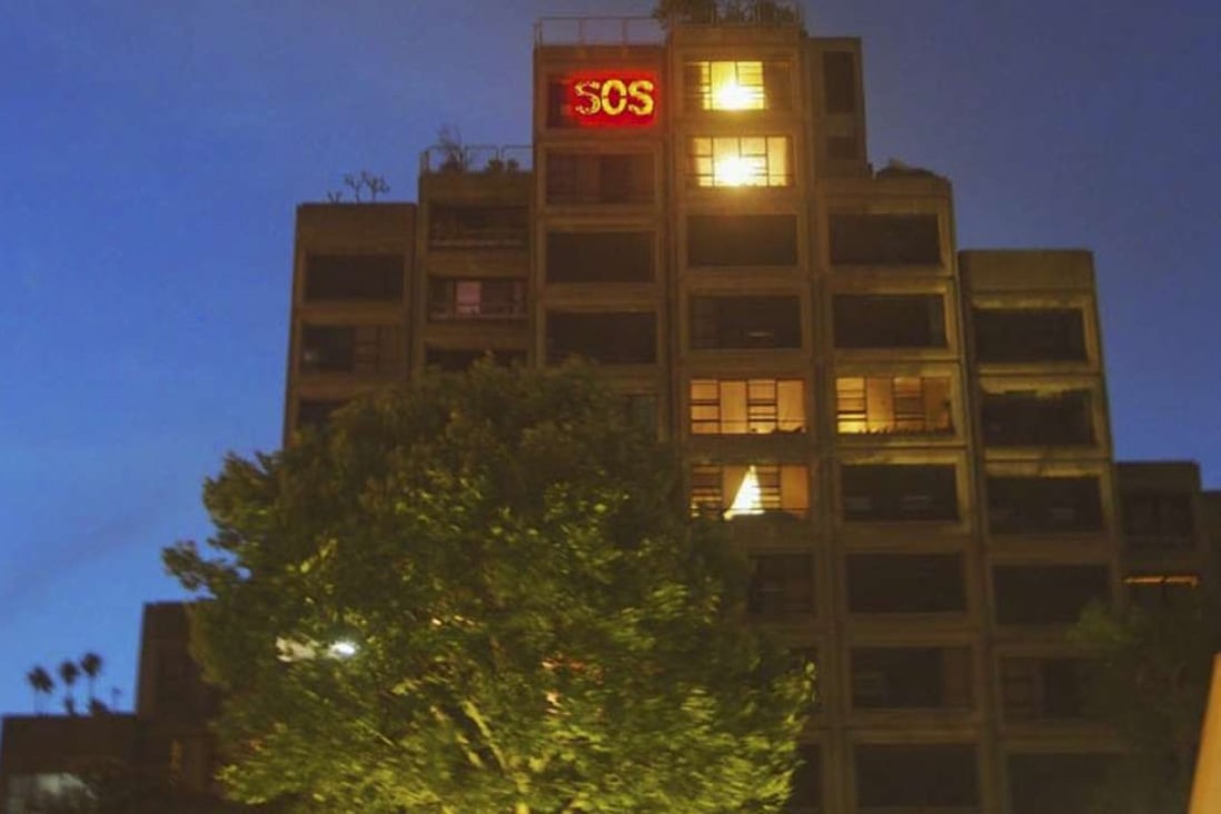 An SOS sign lights up in the window of the home of 90-year-old Myra Demetriou, one of two remaining residents of the Sirius building in Sydney’s Millers Point. Photo: John Dunn