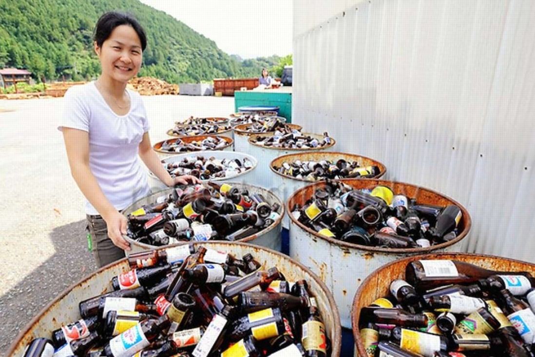 A resident of Kamikatsu shows off recycling bins for brown glass bottles, one of 45 categories into which residents sort their garbage. Photo: YouTube / Seeker Stories