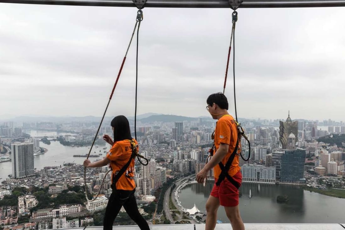 Tourists take part in a "sky walk" on the rim of the 61st floor of the Macau Tower in Macau. Photo: AFP