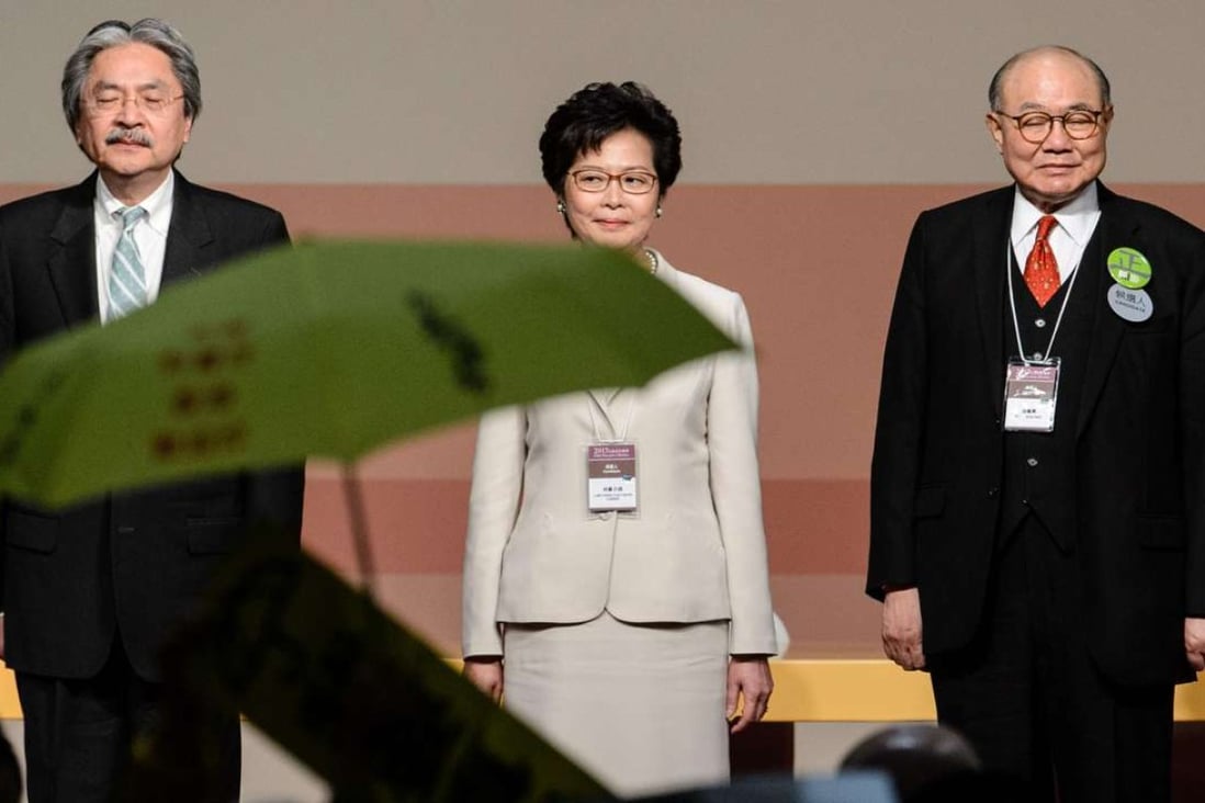 A pro-democracy protester holds up an umbrella after Carrie Lam was declared the winner of the chief executive election on March 26, as she stands flanked by losing candidates John Tsang (left) and Woo Kwok-hing. Photo: AFP