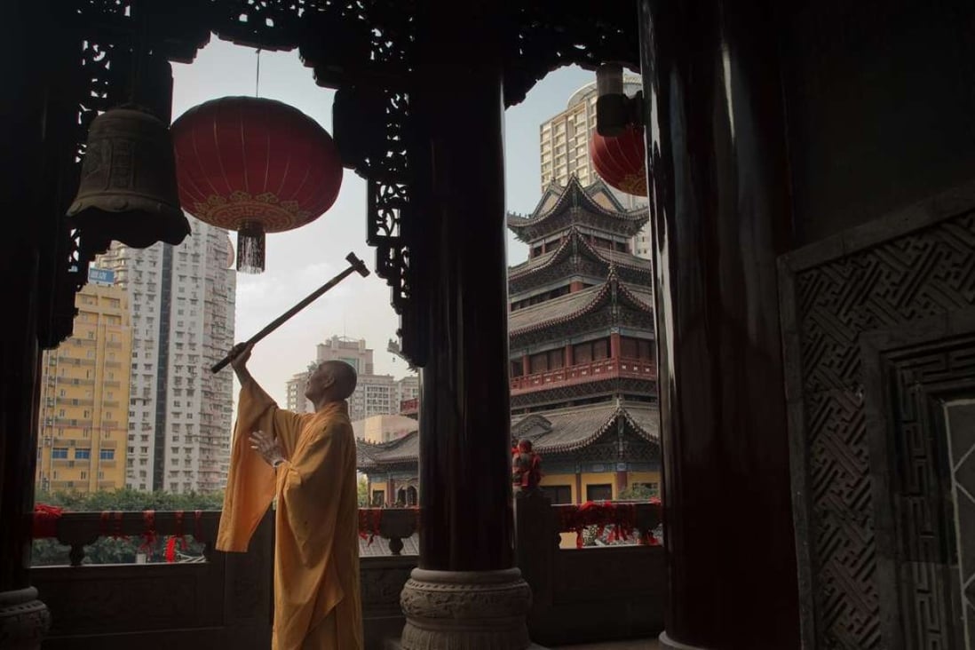 A Buddhist monk rings a bell with a wooden hammer at the Arhat temple in Chongqing. Picture: AFP