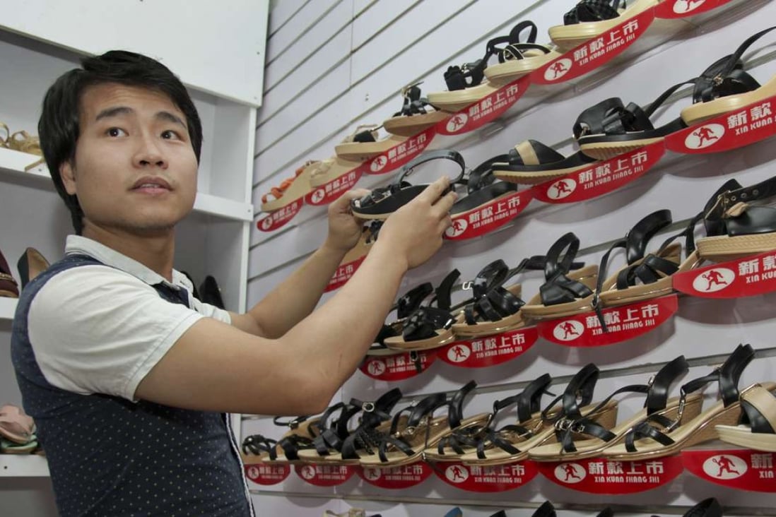 A Chinese salesman adjusts a display as he waits for customers at his shoe shop in Kampala, Uganda. Photo: AP