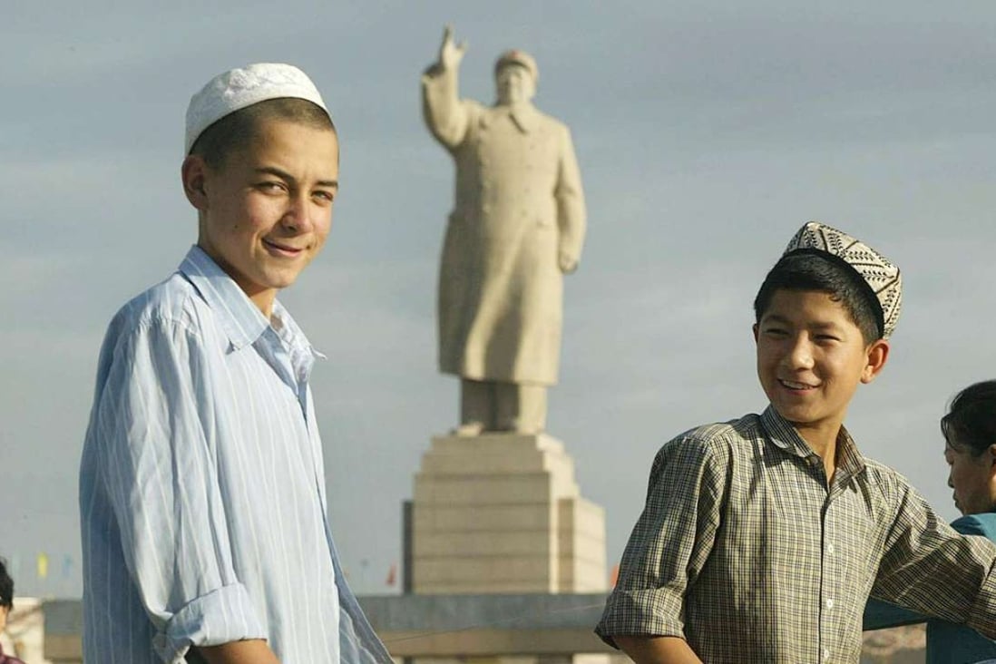 Uygur boys walk past a looming statue of Mao Zedong facing Renmin Square in Kashgar, Xinjiang. Photo: AFP