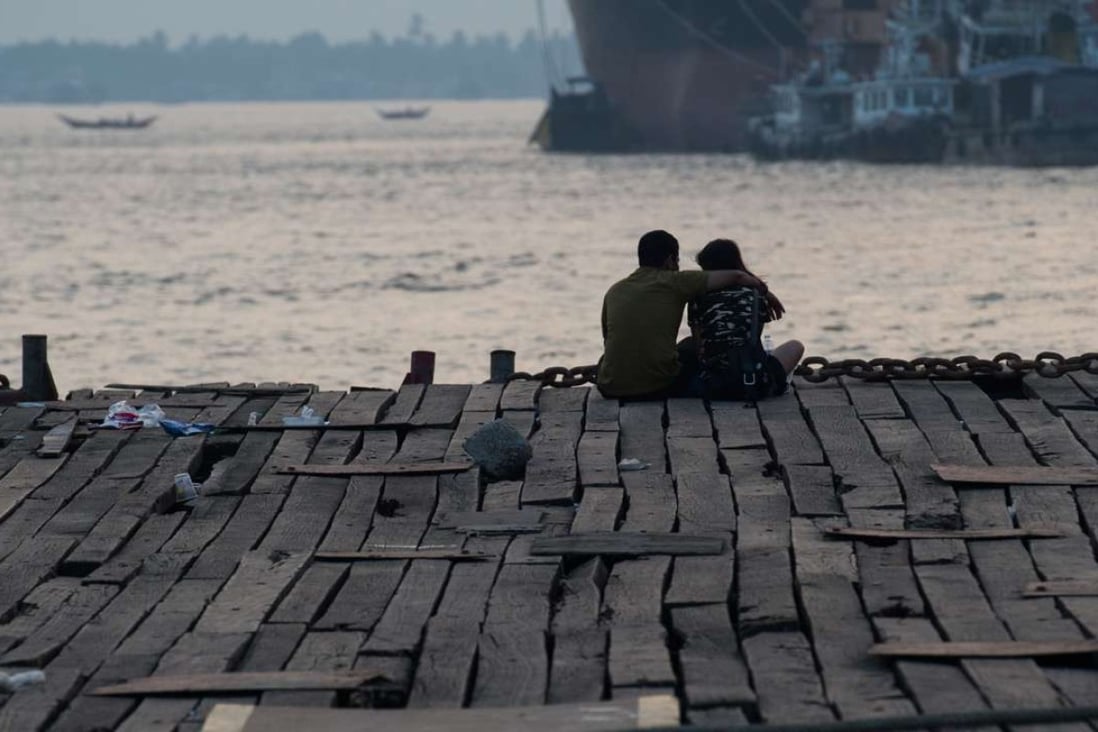 A couple sitting at a jetty during sunset in Yangon. Photo: AFP