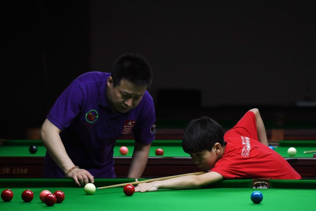 Coach Hu Bing watches over 13-year-old Ma Hailong during practice at the World Snooker College in Beijing. Photo: AFP