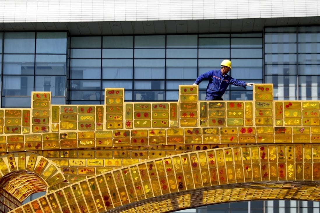 The “Belt and Road Initiative” uses free-trade agreements and infrastructure projects to create a modern Silk Road spanning some 65 countries. Pictured, a worker walks on a “Golden Bridge of Silk Road” structure on display outside the National Convention Centre in Beijing. Photo: AP