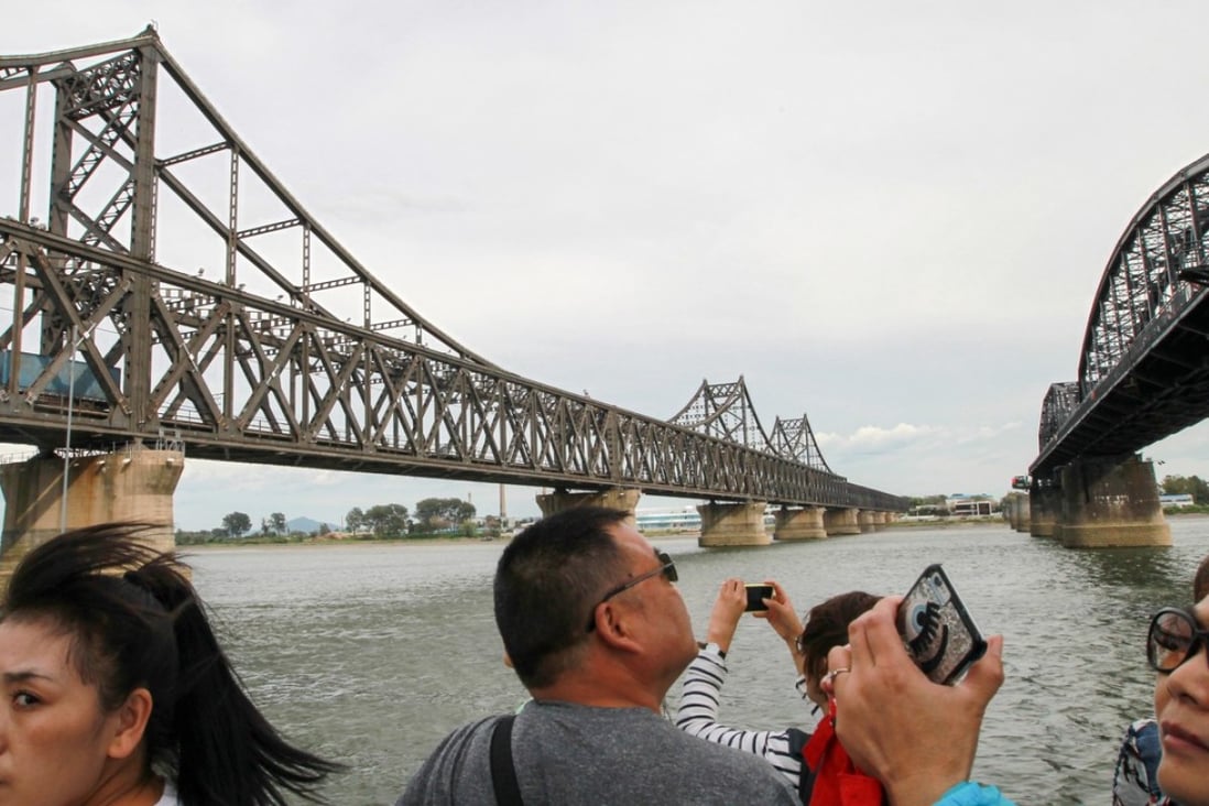 Tourists at the bridge linking North Korea and China (left) across the Yalu River. Photo: Simon Song