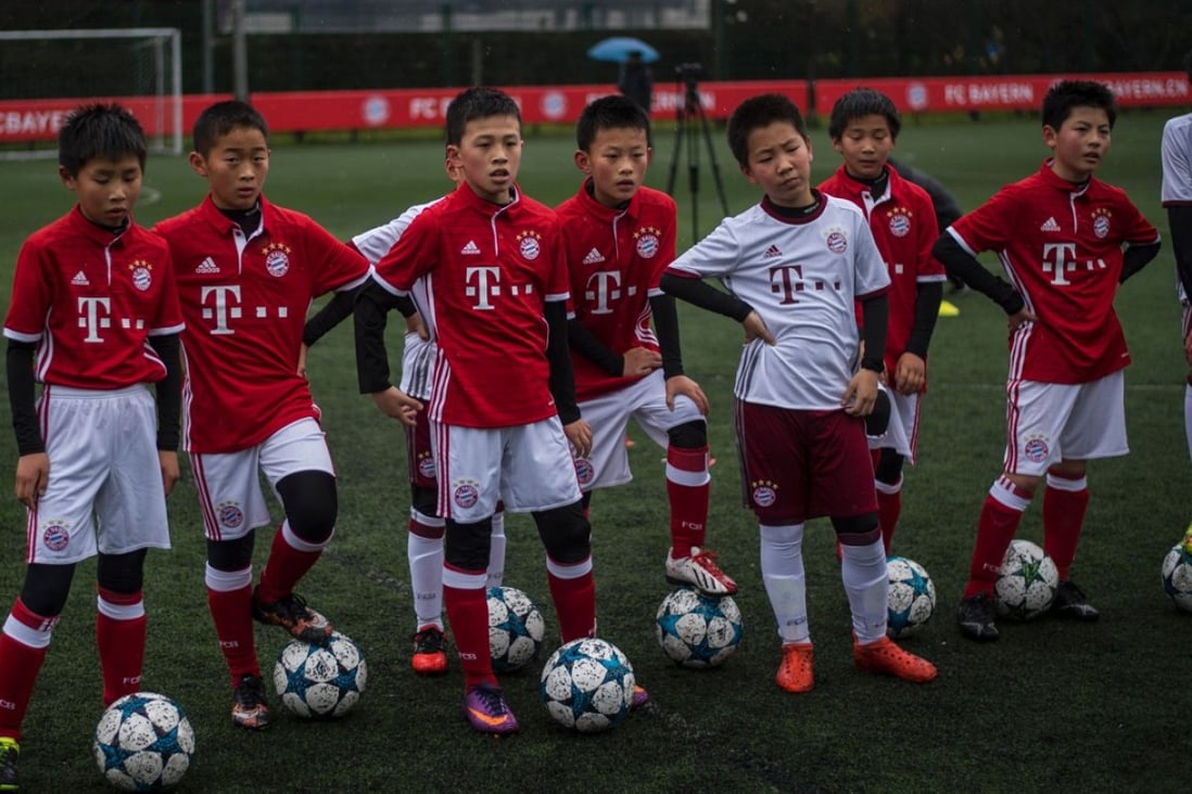 Chinese boys in Bayern Munich jerseys take part in a practise session after the opening ceremony of Bayern's office in Shanghai on March 22, 2017. AFP PHOTO / Johannes EISELE
