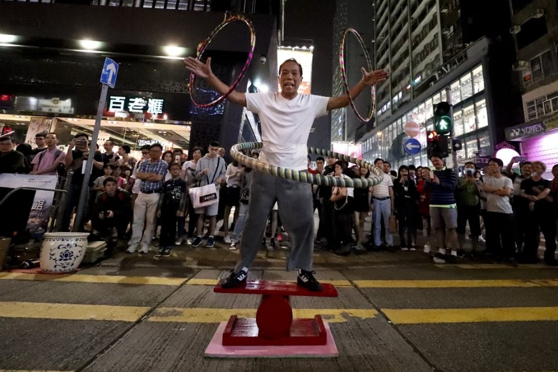 Acrobat Yu Pujiang balances on a rolling cylinder while twirling hula hoops on Sai Yeung Choi Street South in Mong Kok. Photo: James Wendlinger