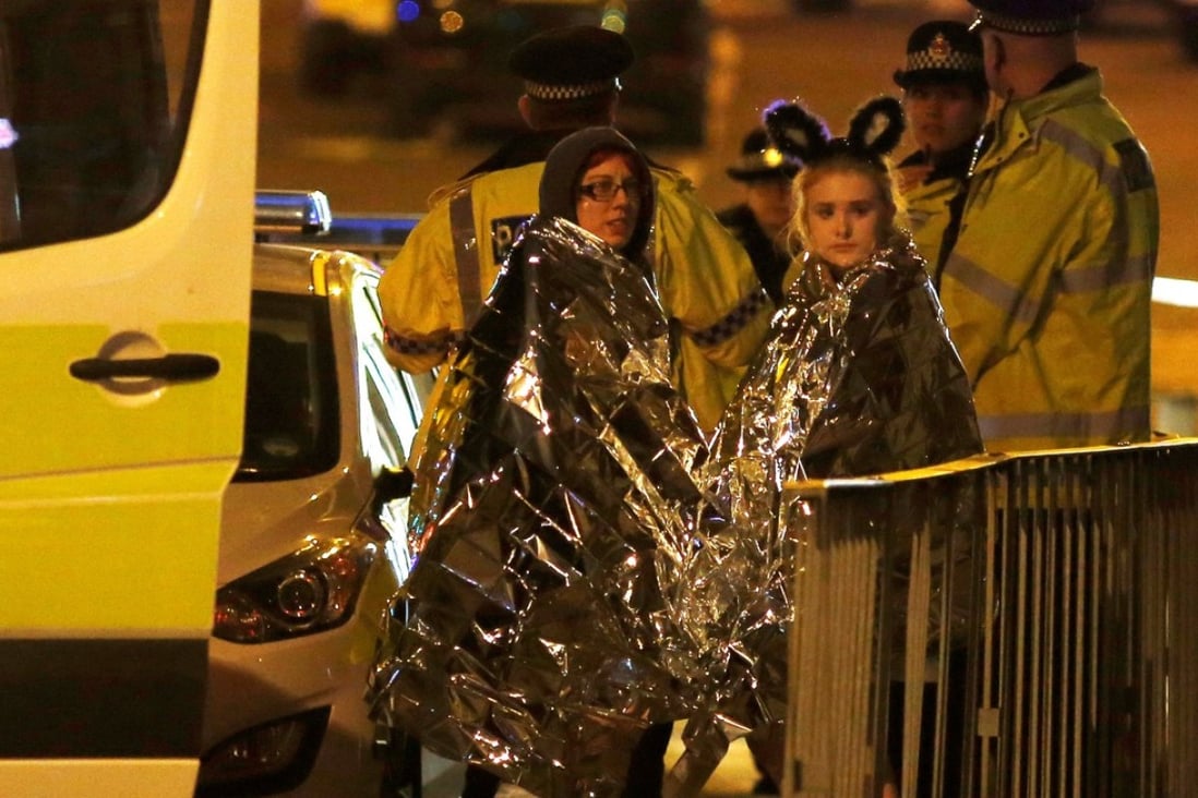 Two women wrapped in thermal blankets stand near the Manchester Arena. Photo: Reuters