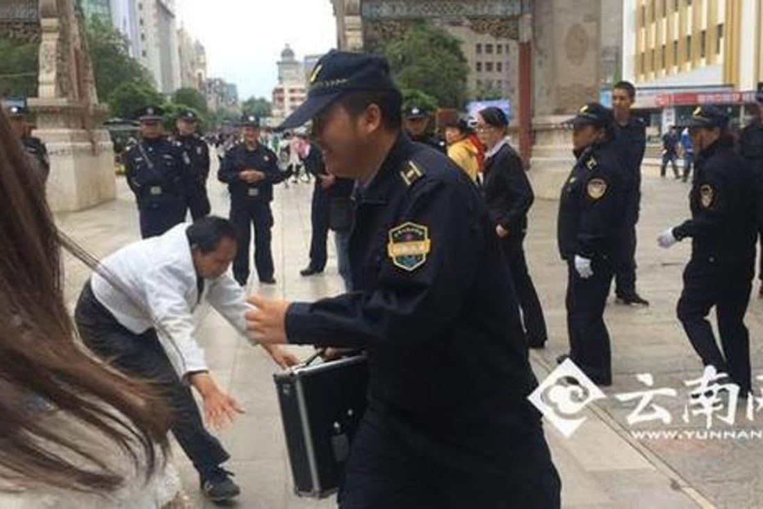 An urban enforcement official in Kunming laughs as a masseur tries to find a loudspeaker telling the public not to use his service. Photo: Yunnan.cn