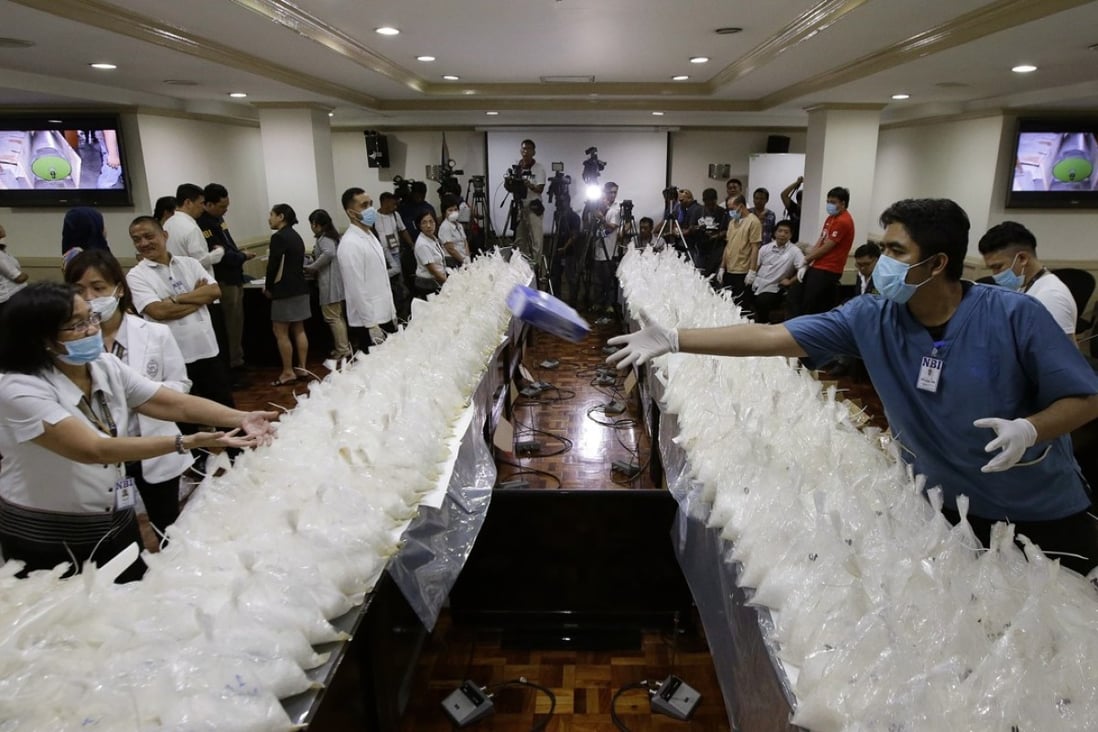 A man passes a box of rubber gloves after they arranged packs of seized methamphetamine at the National Bureau of Investigation in Manila. Photo: AP