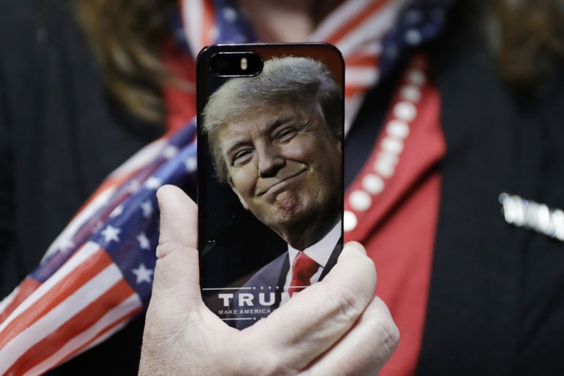 In this 2016 file photo, a woman holds up her cell phone carrying Donald Trump’s picture before a rally with then presidential candidate in Bedford, New Hampshire. Photo: AP