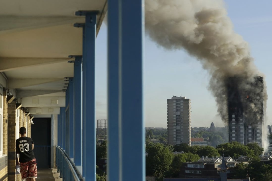 A resident in a nearby building watches smoke rise from a building on fire in London. Photo: AP