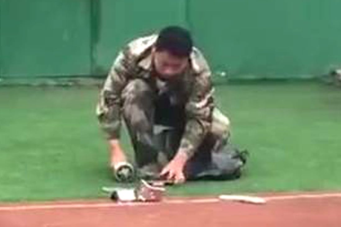 A man in military uniform takes a hammer to a confiscated phone in this screenshot from an online video. Photo: Handset